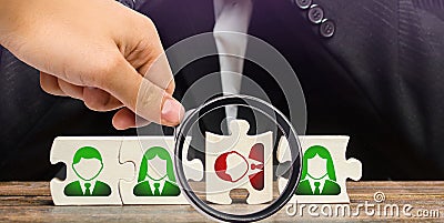 A magnifying glass looks at a businessman sitting in despair over the not assembled puzzles symbolizing a team of employees. Toxic Stock Photo
