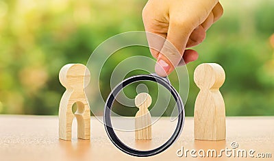 A magnifying glass looks at a childâ€™s figure stands between father and mother. The child chooses which parent to live with after Stock Photo