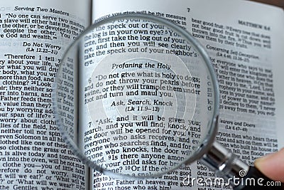 Magnifying glass over open Holy Bible Book, close-up, ask, search, knock verse, Matthew 7:7 Scripture text Stock Photo