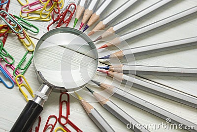 Magnifying glass, pencils on wooden table. Copy space for text. Search idea concept Stock Photo