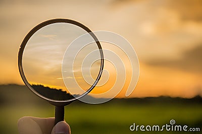 Magnifying glass scan clound and rice green filel on sunset sky Stock Photo
