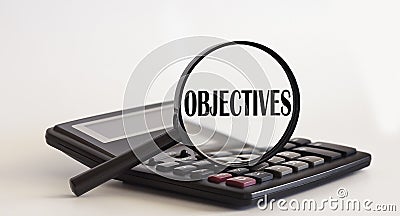 Magnifying glass with text Objectives on calculator Stock Photo