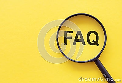 Magnifying glass on wood letters as FAQ abbreviation, frequently asked questions on yellow background Stock Photo