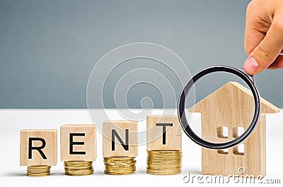 Magnifying glass, wooden blocks with the word Rent, coins and a miniature house. The concept of renting housing and real estate. Stock Photo