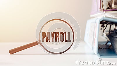 Magnifying glass with the word PAYROLL on office table Stock Photo