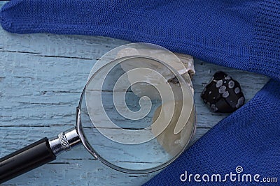 A magnifying lens and three semiprecious stones - stilbite, yellow quartz and snow obsidian Stock Photo