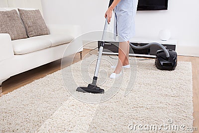 Maid cleaning carpet with vacuum cleaner Stock Photo