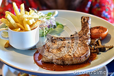 Main course pork t-bone steak with vegetables salad in white dish. Stock Photo