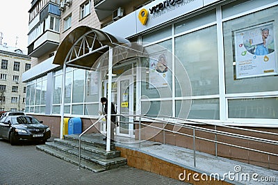 Main entrance to the postal office of the state enterprise Ukrposhta, an old woman client leaving it. Kyiv, Ukraine Editorial Stock Photo