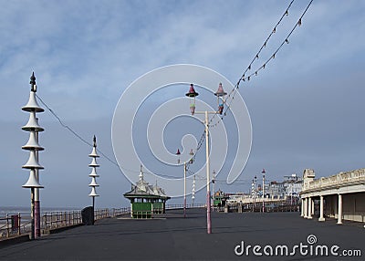 The main promenade in Blackpool with traditional shelters and street lights with a man walking in the distance and town buildings Editorial Stock Photo