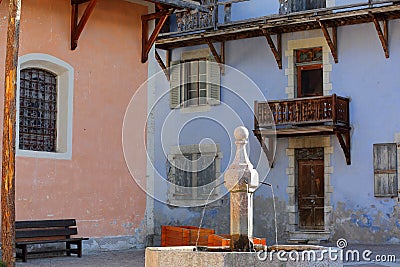 The main square of Ceillac village with a traditional fountain and colorful traditional houses with wooden balconies Stock Photo
