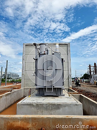 Main tank power transformer Installation on the foundation on clouds in the blue sky background Stock Photo