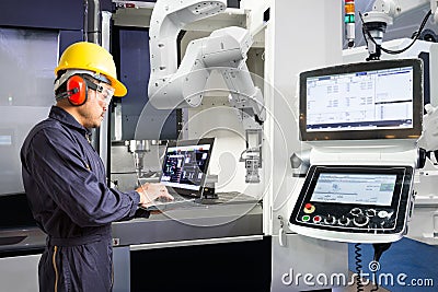 Maintenance engineer using laptop computer control automatic robotic hand with CNC machine in smart factory, Industry 4.0 concept Stock Photo