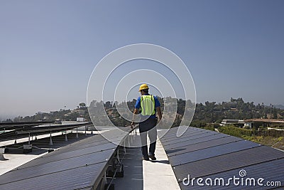 Maintenance Worker Inspecting Solar Panels On Rooftop Stock Photo