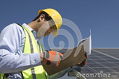 Maintenance Worker Looking At Clipboard Near Solar Panels Stock Photo