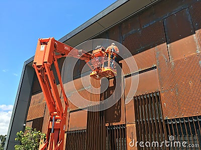 Maintenance Workers on Orange Cherry Picker Crane Editorial Stock Photo