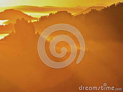 Majestic golden sunrise in a beautiful mountain. Sandstone rock increased from gold foggy valley background. Stock Photo