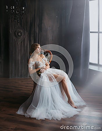 Majestic and proud princess girl in white chic oriental white silver dress tired sitting on chair, lady shows off her Stock Photo