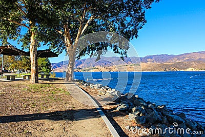 A majestic shot of the still deep blue lake waters, gorgeous mountain ranges and blue sky at Castaic Lake Stock Photo