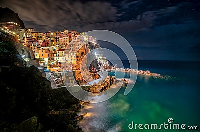 Majestic shot of the turquoise ocean and the lighted coastline of colorful buildings at nighttime Stock Photo