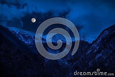 Majestic winter night in a mountain valley with full moon in a starry sky Stock Photo