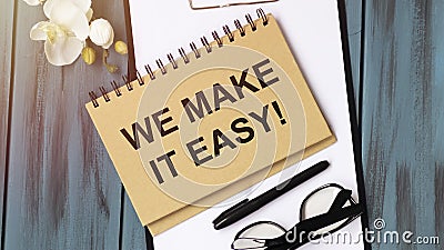 WE MAKE IT EASY. Blue notebook stationery calculator and wooden stamps Stock Photo