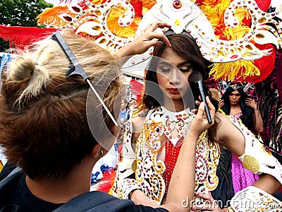 A make up artist applies make up to a parade participant in her colorful costume during the Sumaka Festival in Antipolo City. Editorial Stock Photo