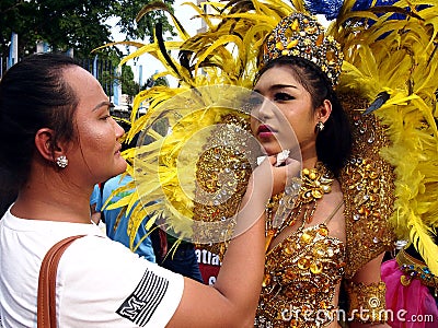 A make up artist applies make up to a parade participant in her colorful costume during the Sumaka Festival in Antipolo City. Editorial Stock Photo