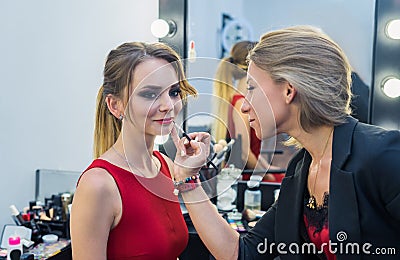 Make-up artist doing smoky eyes makeup to beautiful young girl Stock Photo