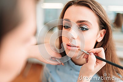 Make up artist hand applying gloss on woman lips Stock Photo