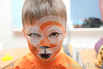 Make up artist making tiger mask for child.Children face painting. Boy painted as tiger or ferocious lion Stock Photo