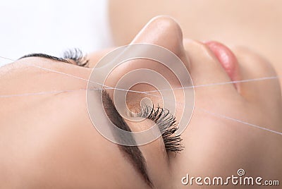 The make-up artist plucks eyebrows with a thread close-up. Women`s cosmetology in the beauty salon Stock Photo
