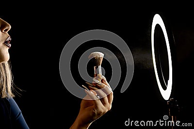 Make-up artist`s hand with makeup brushes in front of a ring lamp against Stock Photo