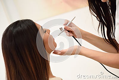 Make-up artist using aerograph making an airbrush make up Stock Photo