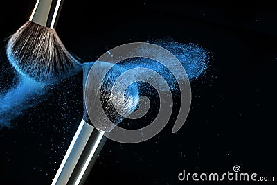 Make-up brush concept with ultraviolet, blue and orange powder explosion isolated on black background. Stock Photo