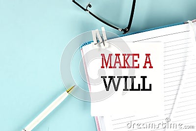MAKE A WILL text on a sticky on notebook with pen and glasses , blue background Stock Photo