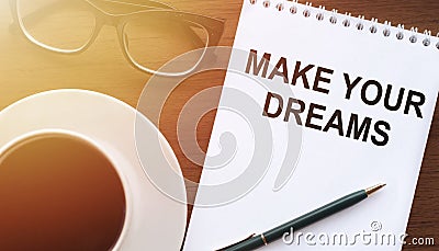 Make your dreams, the text is written on a notebook with glasses and coffee on the table. Sunlight is falling. Concept of desire Stock Photo