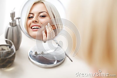 Makeup Applying. Beautiful Woman Looking at Her Face in the Mirror Stock Photo