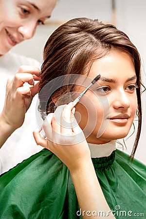 Makeup artist combing eyebrows and hairstylist preparing hairstyle Stock Photo