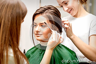 Makeup artist combing eyebrows and hairstylist preparing hairstyle Stock Photo