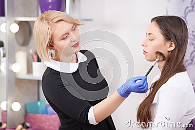 Makeup artist painting blush at cheekbones for woman. Stock Photo