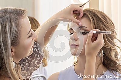 Makeup artist puts make up on girl model. wedding makeup, evening makeup, natural makeup Stock Photo