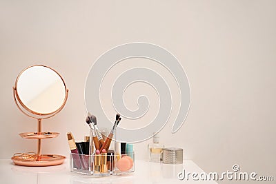 Makeup cosmetic products and tools in organizer on dressing table near color wall Stock Photo