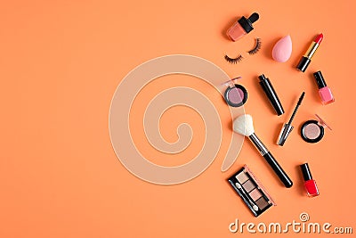 Makeup cosmetics and beauty products spilling out on pastel peach colored background. Flat lay, top view. Beauty salon banner Stock Photo