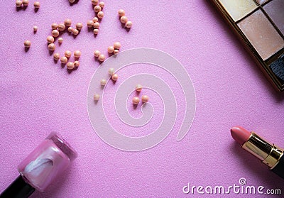 Makeup flat lay with the nail polish, blush powder balls, eyeshadows and lipstick with the pink background - Image Stock Photo