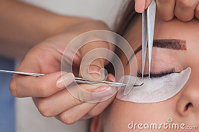 Makeup Master corrects, and strengthens eyelashes beams, holding out a pair of tweezers in a beauty salon. Stock Photo