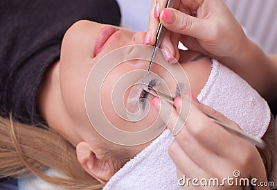 Makeup Master corrects, and strengthens eyelashes beams, holding out a pair of tweezers Stock Photo