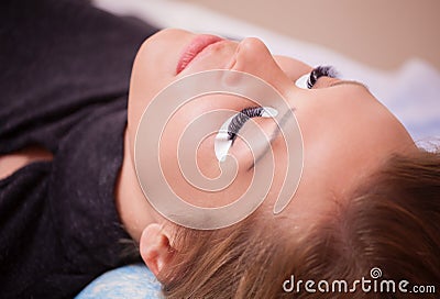 Makeup Master corrects, and strengthens eyelashes beams, holding out a pair of tweezers in a beauty salon. Stock Photo