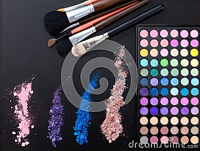 Makeup tools and accessories isolated on black background. Top view and mock up. Lipstick, eye shadows, make up brushes. Stock Photo