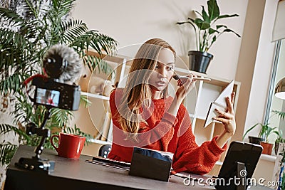 Makeup tutorial. Cute and young blogger using brush to apply highlighter while broadcasting live video to social network Stock Photo